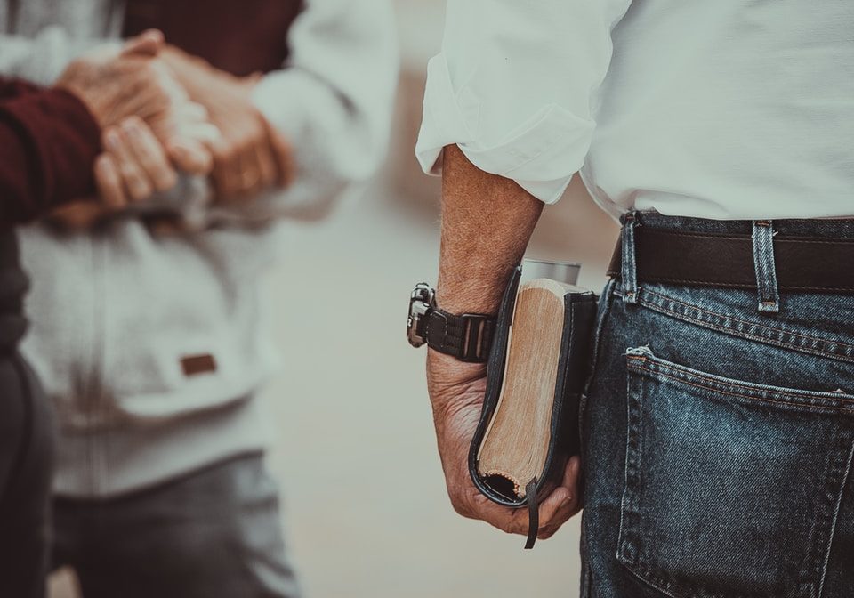 person in white long-sleeved shirt holding book